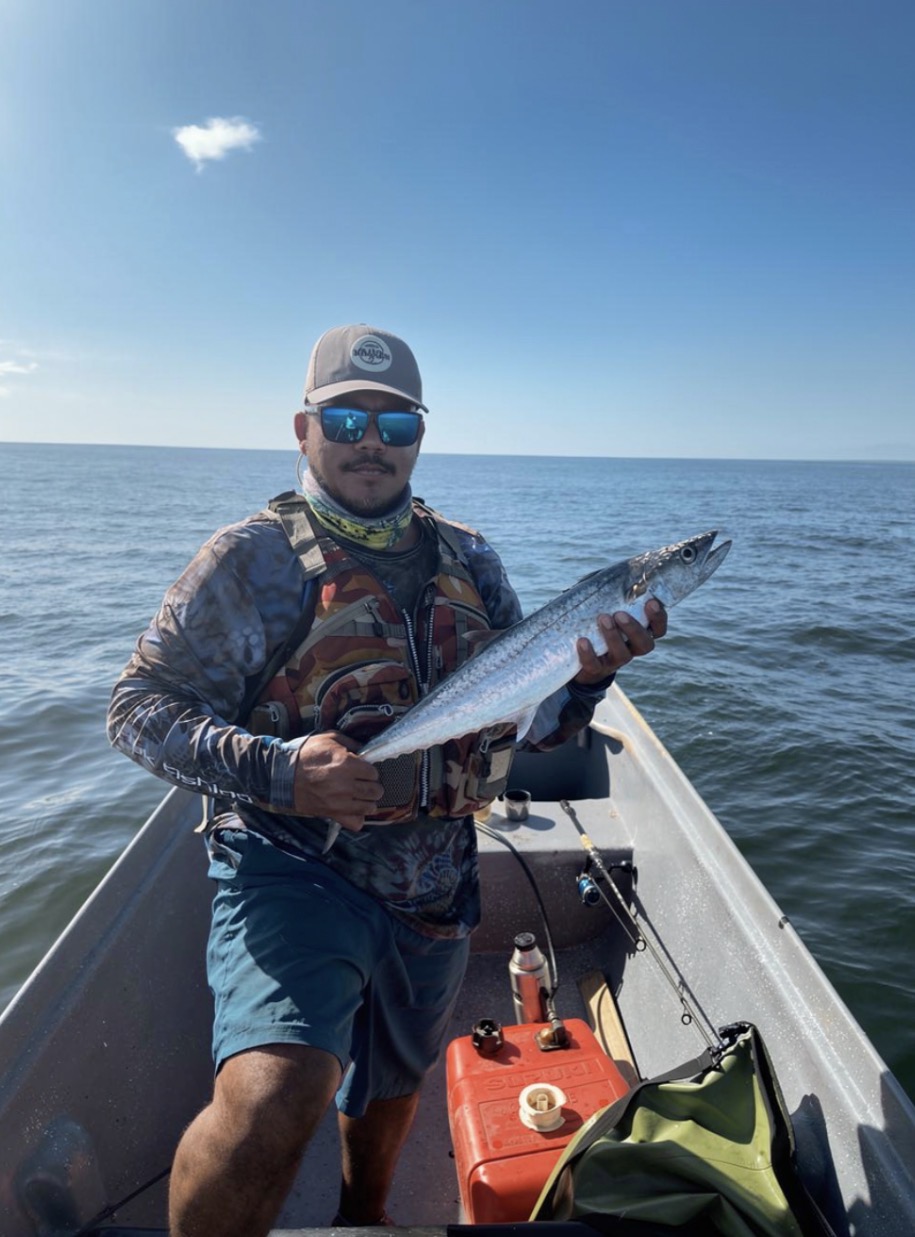 Pescador sosteniendo una macarela capturada
